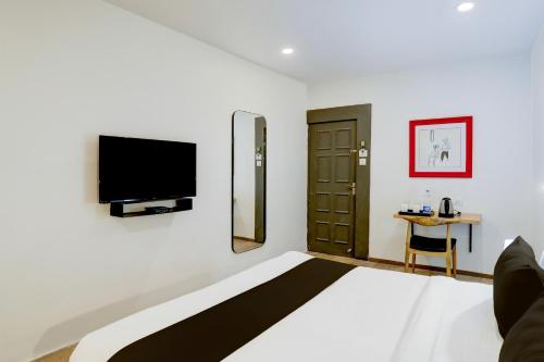 a bedroom with a large bed with a tv on the wall at Super Townhouse Kalmana in Nagpur