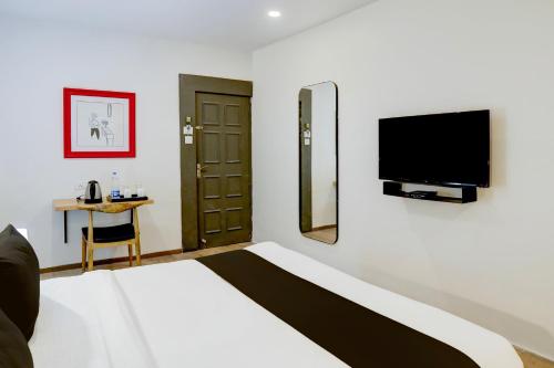 a bedroom with a bed and a tv on a wall at Super Townhouse Kalmana in Nagpur