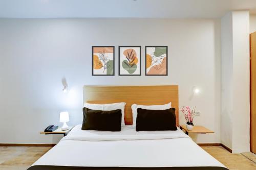 a bedroom with a large white bed and some pictures on the wall at Super Townhouse Kalmana in Nagpur