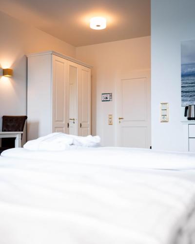 a bedroom with a bed and a white cabinet at Hotel Villa Tripaldi in Schönberg in Holstein