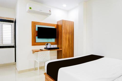 a bedroom with a bed and a desk and a tv at Super Townhouse Rajahmundry in Rājahmundry