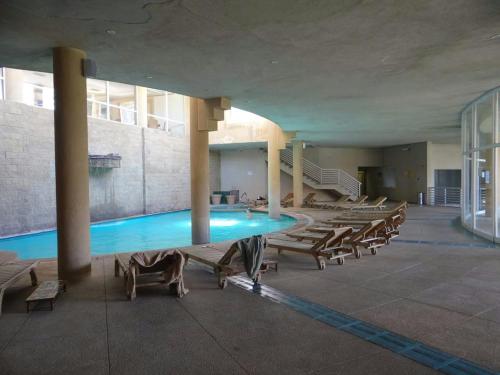 a swimming pool in a building with a bunch of chairs at Departamento Full Equipado in Concón