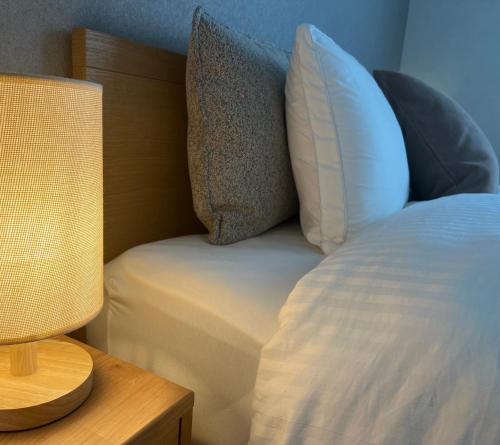a bed with a pillow and a lamp on a table at VJ House in Fukuoka