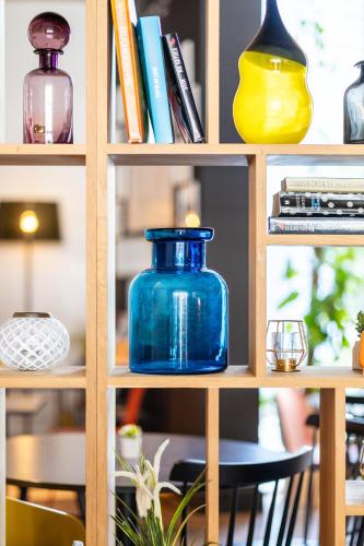 a book shelf with a blue glass jar on it at Holiday Inn Express Mechelen City Centre by IHG in Mechelen