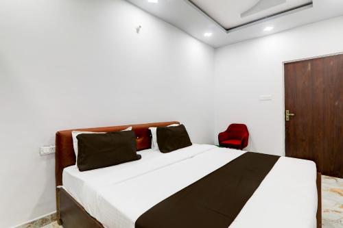 a bedroom with a bed and a red chair at Hotel O Star Inn Hotel in Lucknow