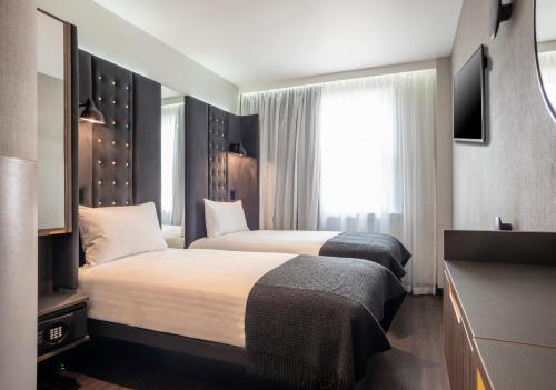 a hotel room with two beds and a window at Point A Hotel London Paddington in London