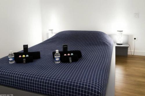 a blue checked bed with bottles of water on it at Le Nid Mâconnais Central - Gare - Calme in Mâcon