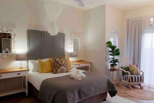 a bedroom with a large bed and a chair at Self Catering Apartment - De Kelders in De Kelders