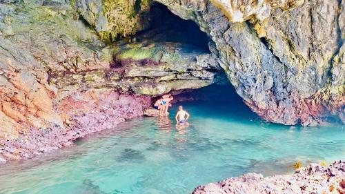 a couple of people standing in the water in a cave at Self Catering Apartment - De Kelders in De Kelders