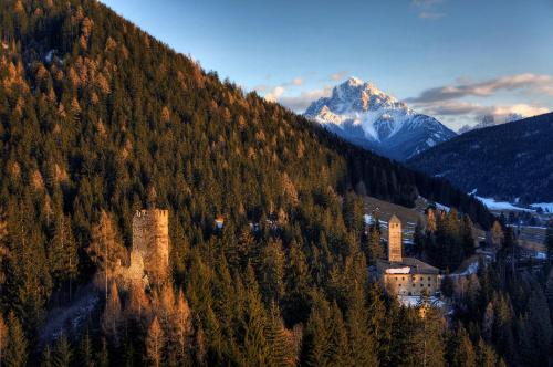 a castle on the side of a hill with a mountain at Pension Panorama in Monguelfo