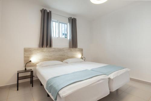 a white bed in a white room with a window at La Lajita Beach House in La Lajita