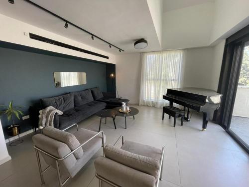 a living room with a couch and a piano at Modern Jem in Jerusalem in Geʼullim