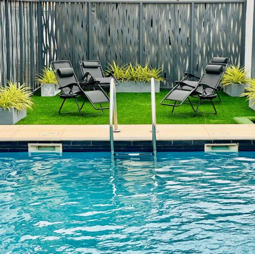 a group of chairs sitting next to a swimming pool at Jessica's Villa in Accra