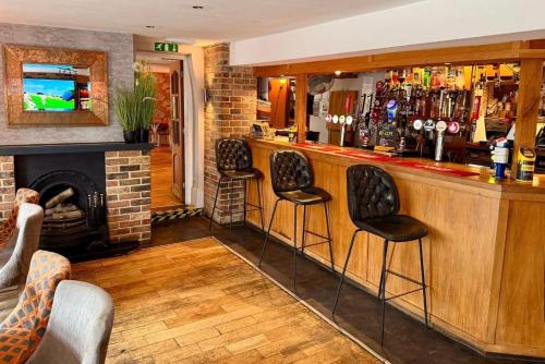 a bar with three stools in a room with a fireplace at The Anchor Inn in Sutton Bridge
