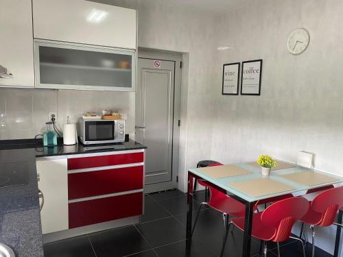 a kitchen with red and white cabinets and a table with a microwave at S. Mamede House - Penafiel in Recezinhos