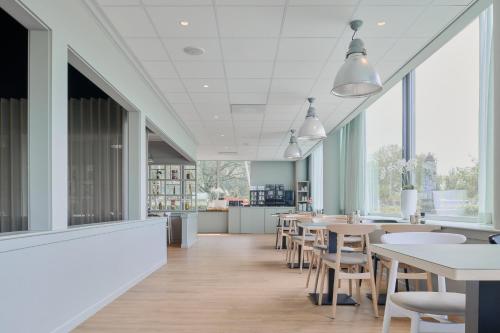 a dining room with tables and chairs and windows at Garner Hotel Maastricht by IHG in Maastricht