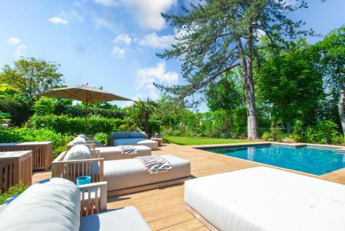 a backyard with a swimming pool and a patio with couches and a pool at Demeure Architecte avec Piscine Privee in Le Vésinet