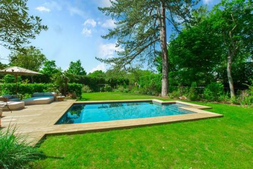 a backyard with a swimming pool and a lawn at Demeure Architecte avec Piscine Privee in Le Vésinet