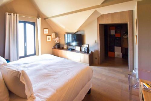 a bedroom with a large white bed and a tv at Demeure Architecte avec Piscine Privee in Le Vésinet