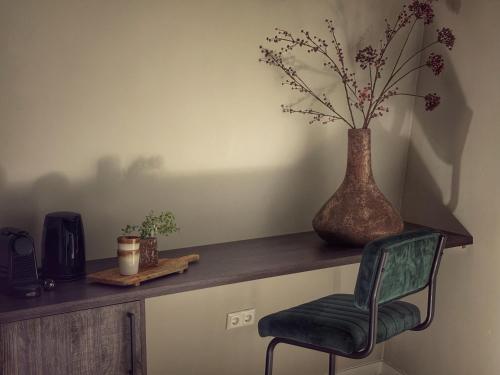 a chair sitting on a wooden shelf with a vase at De Meuleberg Boutique Suites 