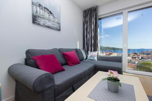 a living room with a gray couch with pink pillows at Royal Primošten in Primošten
