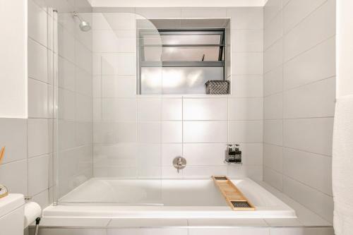 un bagno bianco con vasca e specchio di Cityescapes 2F in Waterfall Midrand - Beautiful self catering 2 bedroom unit next to Kyalami Racetrack with free WiFi swimming pool gym and restaurant - Perfect for a small family a Midrand