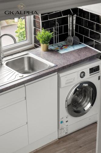 a kitchen with a sink and a washing machine at 33A Castle Street - Contractor-Friendly 2-Bedroom Apartment in Reading City Centre with Wi-Fi, Parking & Long Stay deals in Reading