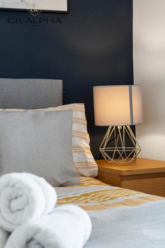 a bedroom with a bed with a lamp on a table at 33A Castle Street - Contractor-Friendly 2-Bedroom Apartment in Reading City Centre with Wi-Fi, Parking & Long Stay deals in Reading