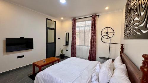 a bedroom with a white bed and a television at Domin Homestay in Arusha