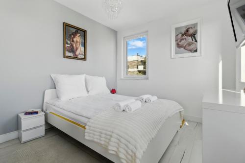 a white bedroom with a bed with towels on it at Pełczyńskiego Comfort Stay by Solarento in Warsaw