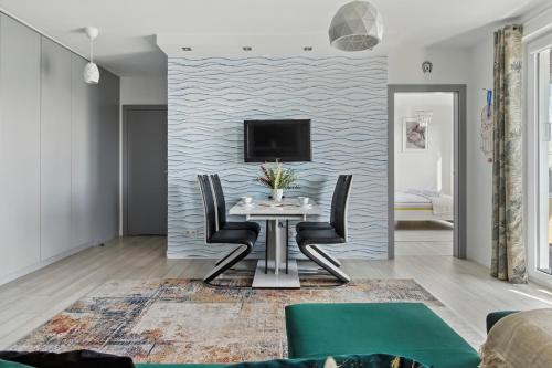 a dining room with a table and a tv on a wall at Pełczyńskiego Comfort Stay by Solarento in Warsaw