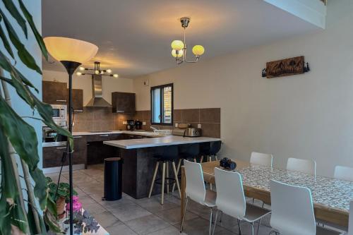 a kitchen with a table and white chairs at L'étoile des Glaciers - Jacuzzi - Piscine - Hammam - ALPES HUEZ in Le Bourg-dʼOisans