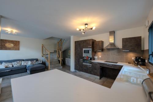 a large kitchen and living room with a blue couch at L'étoile des Glaciers - Jacuzzi - Piscine - Hammam - ALPES HUEZ in Le Bourg-dʼOisans