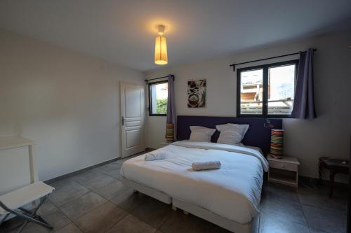 a bedroom with a large white bed and two windows at L'étoile des Glaciers - Jacuzzi - Piscine - Hammam - ALPES HUEZ in Le Bourg-dʼOisans