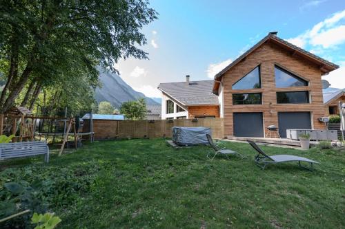 a yard with two chairs and a house at L'étoile des Glaciers - Jacuzzi - Piscine - Hammam - ALPES HUEZ in Le Bourg-dʼOisans