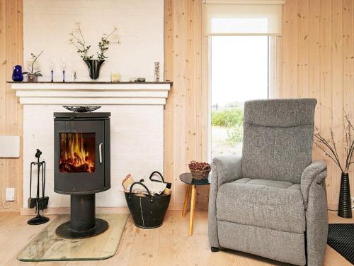 a living room with a chair and a fireplace at Cozy Coastal Retreat in Vorupor-By Traum in Thisted