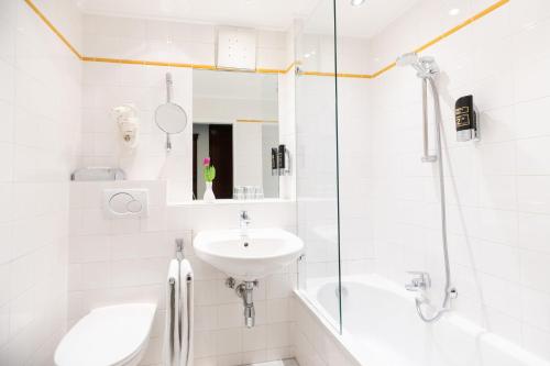 a white bathroom with a sink and a shower at Garner Hotel Vienna - Prinz Eugen by IHG in Vienna