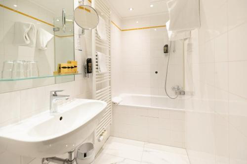 a white bathroom with a sink and a bath tub at Garner Hotel Vienna - Prinz Eugen by IHG in Vienna