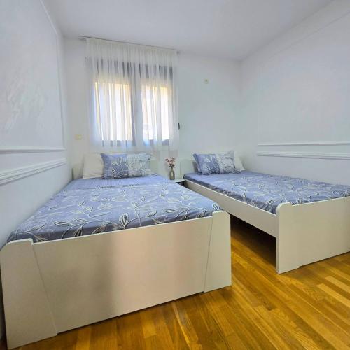 two beds in a room with white walls and wood floors at Apartment Nemanja by Princess Milena in Čučići