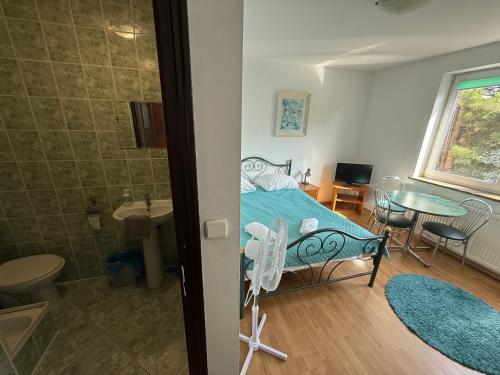 a bedroom with a bed and a table and a bathroom at VITA Augustów in Augustów