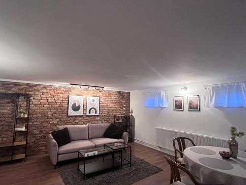 a living room with a couch and a brick wall at Private Apartment & rooms near fairground Hannover in Hannover