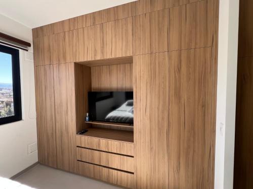 a bedroom with a tv in a wooden wall at Monoambiente de Lujo en la Chura TARIJA! in Tarija