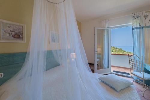 a bedroom with a bed with a mosquito net at Hotel Gallo Nero in SantʼAndrea
