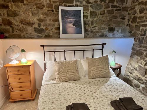 une chambre avec un lit et un mur en pierre dans l'établissement La Petite Bastide-Central Apartment in Neffies, à Néffiès