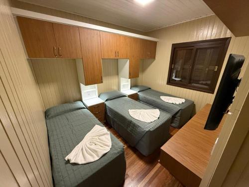 a small room with two beds and a tv at Sua Casa no Centro Gramado, 1km Rua Coberta in Gramado