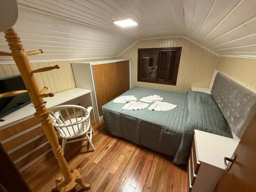 a small room with a bed and a chair at Sua Casa no Centro Gramado, 1km Rua Coberta in Gramado