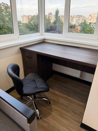 a office with a desk and a chair and two windows at Апартаменти ВІП вул Під Голоском 15 б 9-1 in Lviv