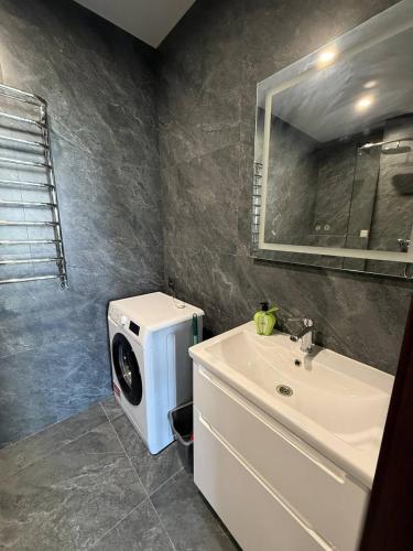 a bathroom with a washing machine next to a sink at Апартаменти ВІП вул Під Голоском 15 б 9-1 in Lviv