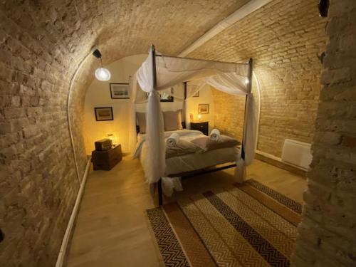 a bedroom with a canopy bed in a brick wall at DIEPPE GITES BEAUREGARD in Dieppe