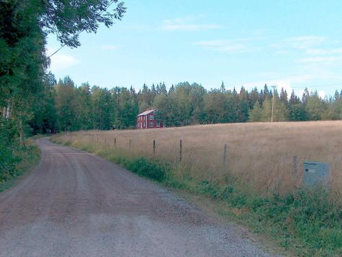 a dirt road with a red house in the middle of a field at 4 person holiday home in BRUA KULLA-By Traum in Källekulla